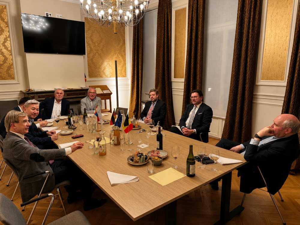 Gesprächsrunde an einem Konferenztisch in Brüssel, auf dem Tisch stehen die deutsche, die europäische und weitere Flaggen.