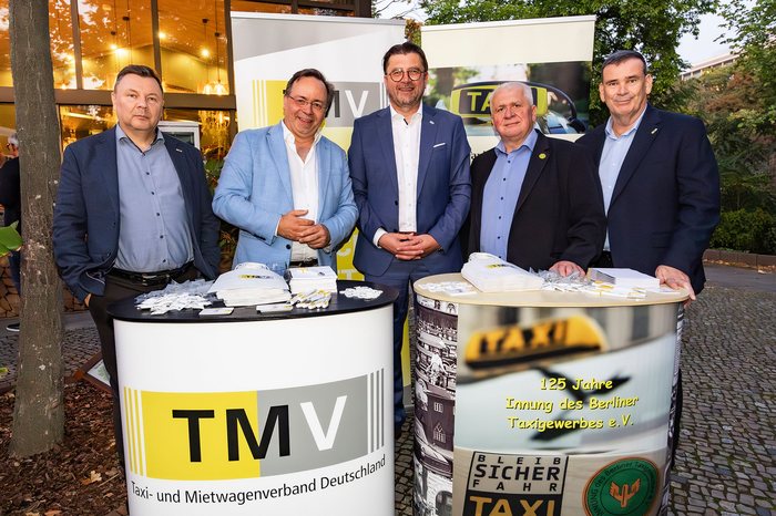 Fünf Personen stehen vor einem Messestand des Taxi- und Mietwagenverbands Deutschland.